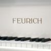 Feurich Logoprägung auf einem weißen Flügel